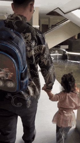 a little girl holds a man 's hand while walking down stairs