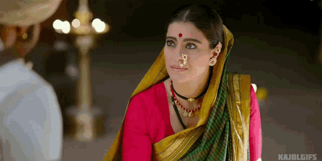 a woman with a nose ring is wearing a pink top