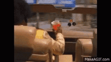 a man is sitting in a chair holding a cup of soda .