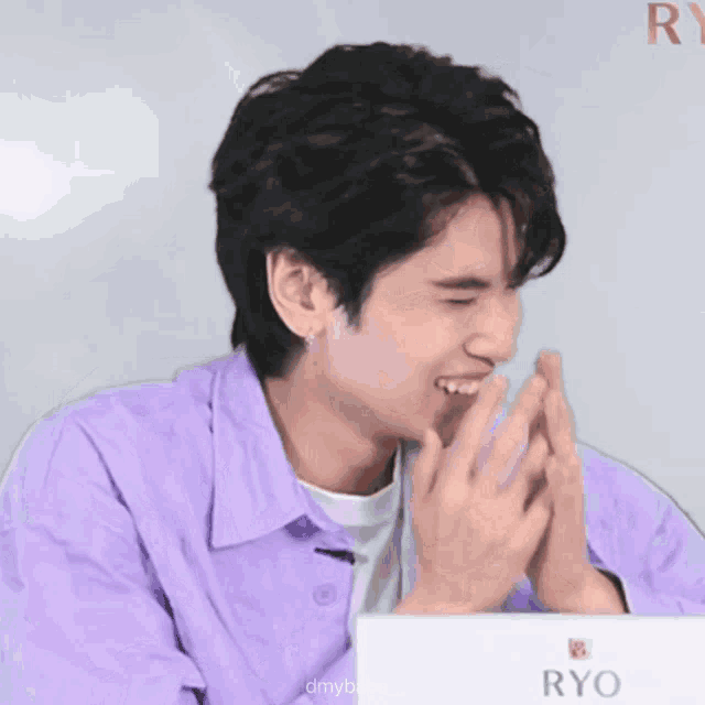 a young man in a purple shirt is clapping his hands