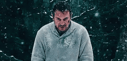 a man in a sweater is standing in the snow with snow falling on him .