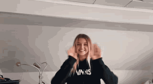 a girl wearing a black vans sweatshirt is making a funny face