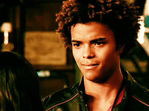 a man with curly hair wearing a black leather jacket