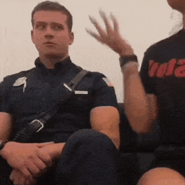 a man in a firefighter uniform sits next to a woman wearing a black shirt that says vol2