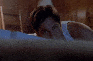 a man in a white tank top is laying on the floor with his arms outstretched