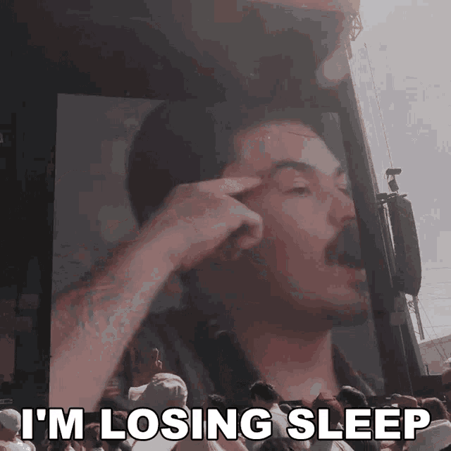 a man in front of a large screen with the words i 'm losing sleep