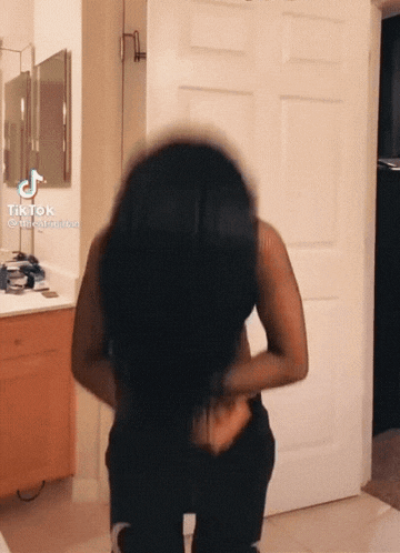 a woman is standing in front of a door with tiktok written on the bottom left