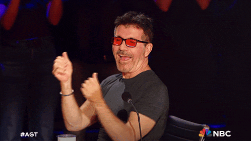 a man wearing red glasses is sitting in front of a microphone with a nbc logo on the bottom right