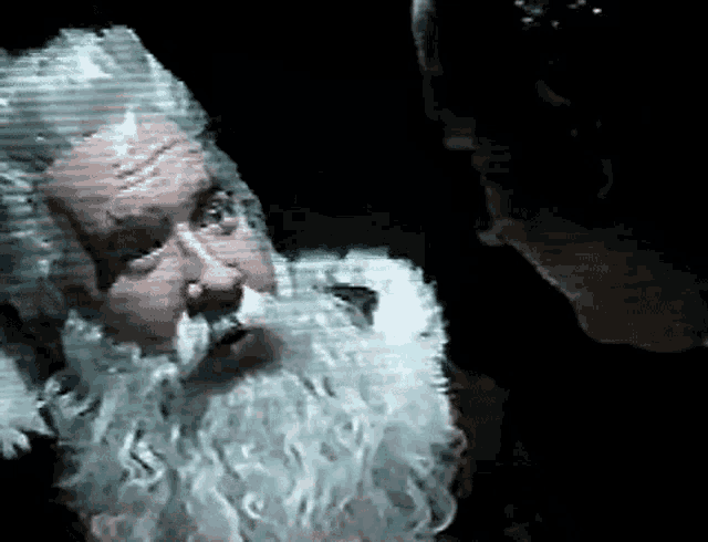 a close up of a man with a beard in a dark room