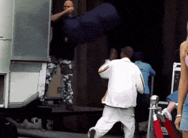 a man in a white jacket is standing in front of a trailer