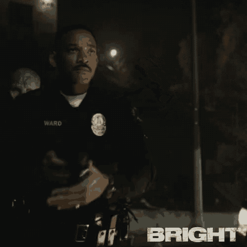 a man in a police uniform is holding a gun in front of a building .