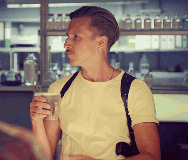 a man in a yellow shirt is holding a mug in his hand