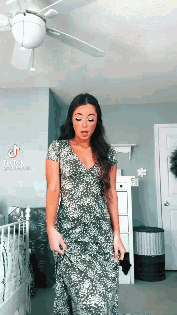 a woman in a leopard print dress is standing in a room with a ceiling fan ..