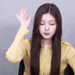 a woman with long hair is wearing a yellow shirt and making a face .