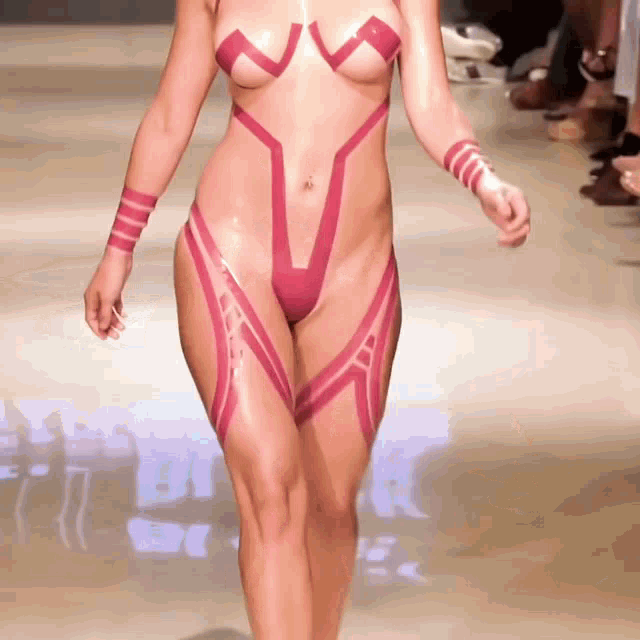 a woman is walking down a runway wearing a very revealing pink bodysuit