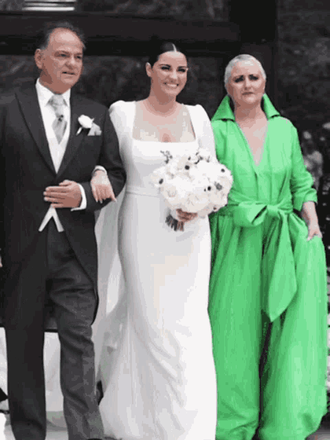 a woman in a green dress is standing next to a bride
