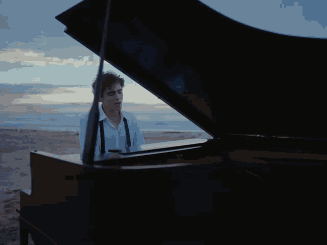 a man is playing a piano on the beach