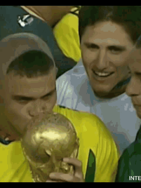 a man in a yellow shirt is holding a trophy with the word inte on it