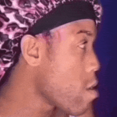 a close up of a man wearing a leopard print hat and making a funny face .