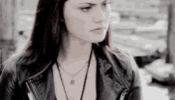 a woman in a leather jacket and necklace is looking at the camera .