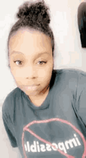 a woman is wearing a black t-shirt with a red circle on it and a bun .