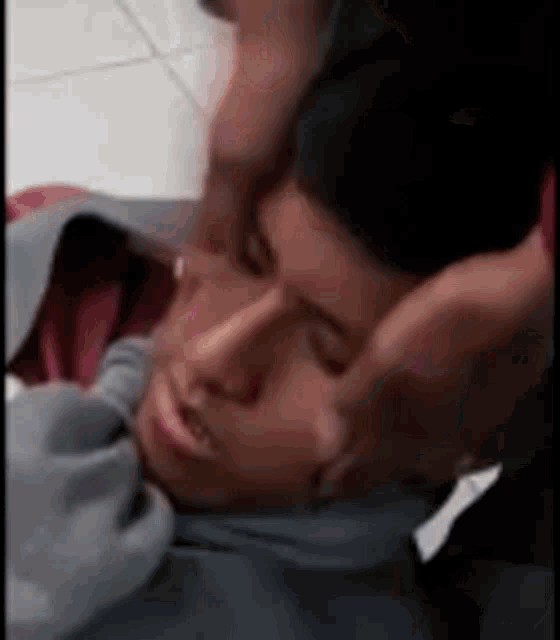 a person is laying on the floor with their head on someone 's chest .