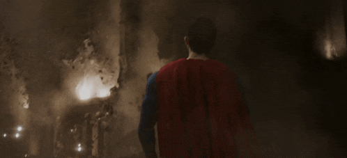 a man in a superman suit stands in front of a fire