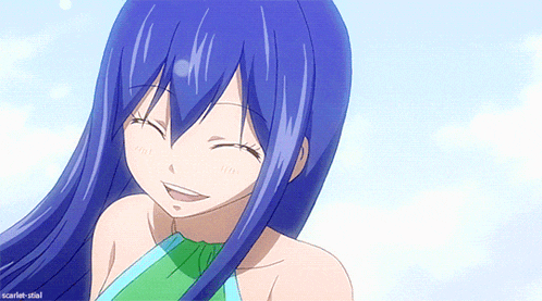 a girl with blue hair and a green top smiles for the camera