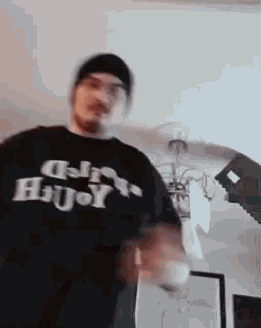 a man wearing a black t-shirt that says `` busy '' is standing in front of a lamp .