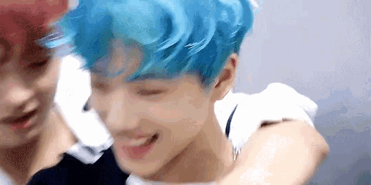 a man with blue hair is being hugged by another man .
