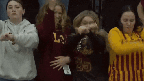 a group of girls wearing sweatshirts with the letter l on them are dancing