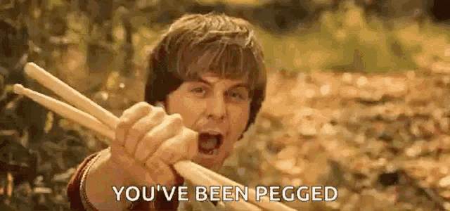 a man is holding a pair of drumsticks in his hand and screaming .