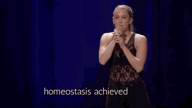a woman is singing into a microphone while standing on a stage