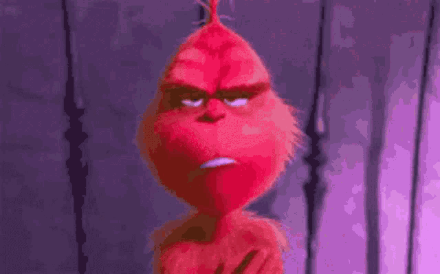 a close up of a red cartoon character with a purple background making an angry face .