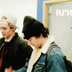 two young men are standing next to each other in front of a door that says norway