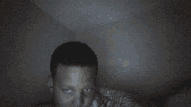 a person is laying in a dark room with a striped blanket
