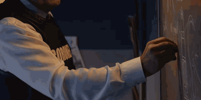 a man wearing a shirt that says ' browns ' is writing on a blackboard