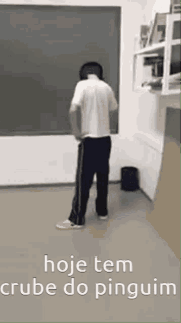 a man is standing in front of a blackboard with the words hoje tem crube do pinguim on the bottom