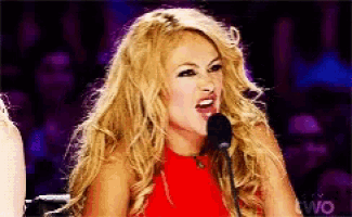 a blonde woman in a red dress is singing into a microphone on tv