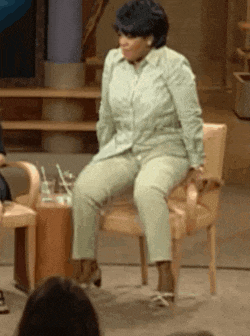 a woman in a green shirt and pants sits in a chair
