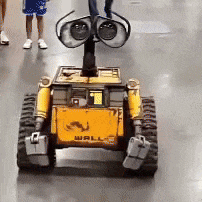 a yellow wall e robot is driving down the floor