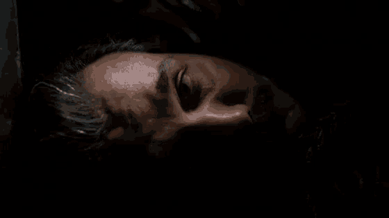 a close up of a man 's face laying down in a dark room .