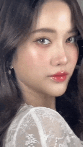 a close up of a woman 's face with a white lace top on