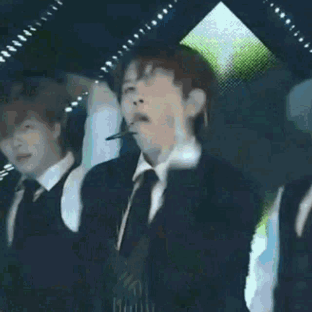 a man in a suit and tie is wearing a microphone and dancing on a stage .