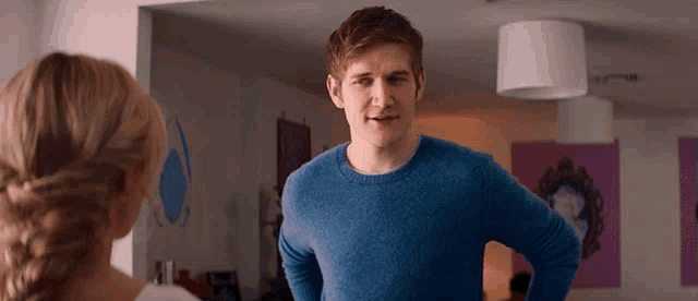 a man in a blue sweater is standing next to a woman