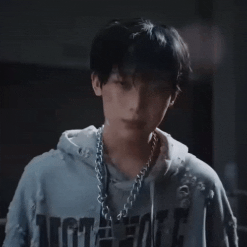 a man wearing a hoodie and a chain around his neck is being hit with a glove .