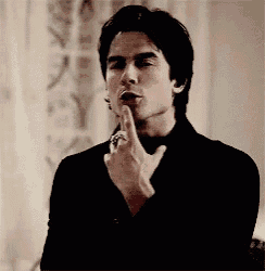 a man in a black suit is making a gesture with his finger .