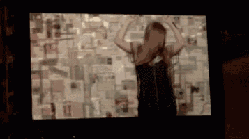 a woman is dancing in front of a wall full of cards