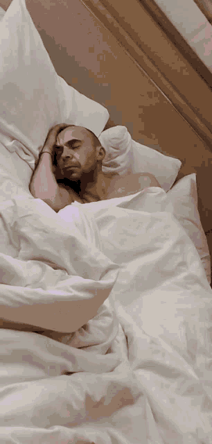 a man laying in bed with his hand on his head