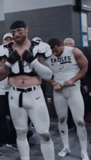 two men in white eagles uniforms are standing in a room